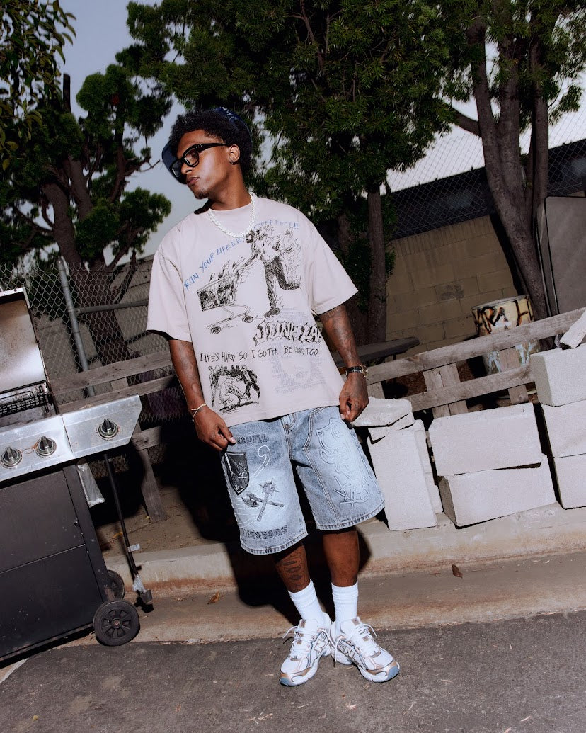 Person wearing a Junk Lab Clothing Graphci t-shirt and shorts standing outdoors with trees and buildings in the background